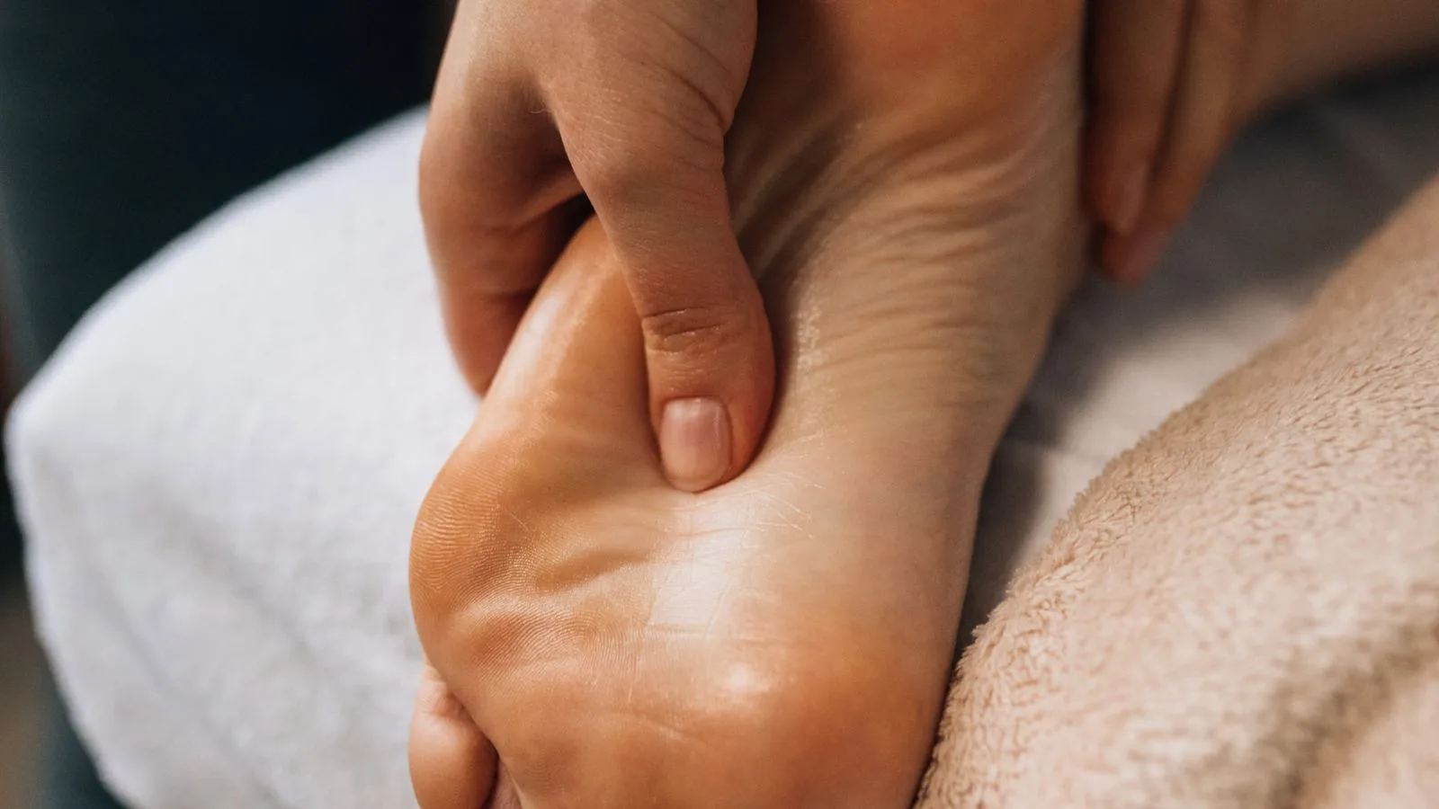 Therapeutin arbeitet mit dem Daumen an der Fusssohle einer Patientin