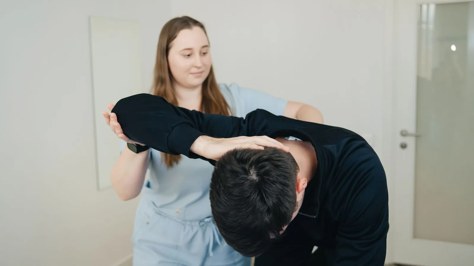 Physiotherapeutin führt einen Patienten durch eine Beweglichkeitsübung